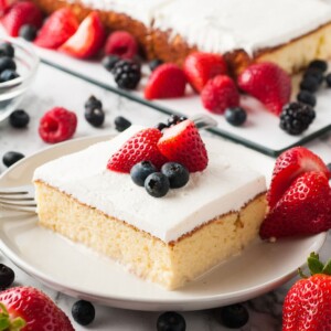 a slice of tres leches cake on a white plate with berries