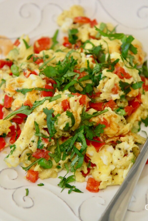 scrambled eggs with peppers and onions. On a plate with a fork.