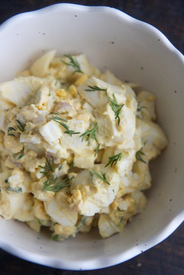 classic egg salad in a white bowl with fresh dill on top