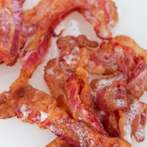 one pound of crispy bacon up close on a white chopping board.