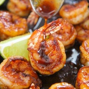 honey chili lime shrimp up close with a spoon drizzling sauce on top.