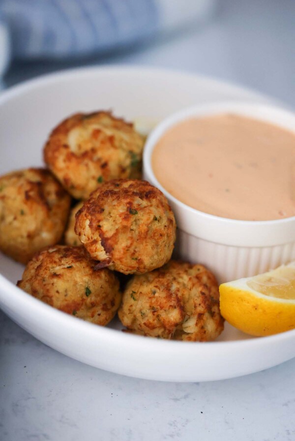 crab bites with a side of remoulade sauce and a lemon wedge.