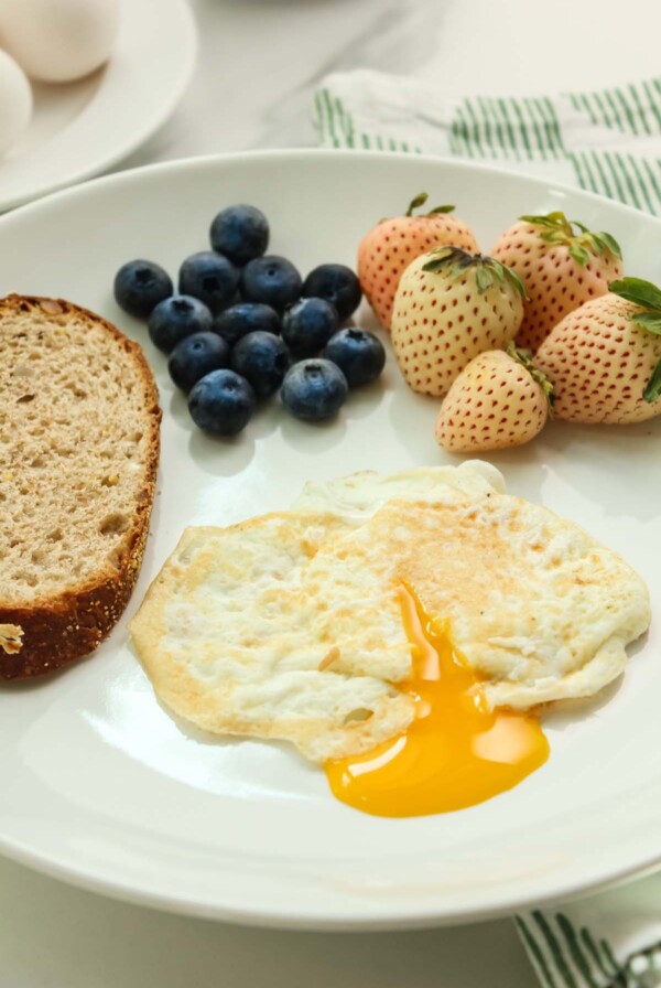over easy egg with runny yolk, toast, and berries on the side.