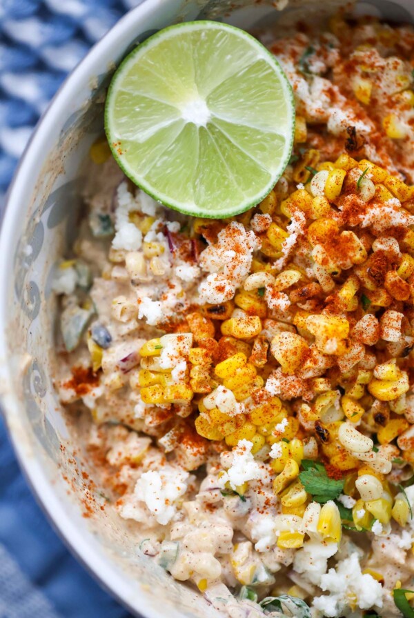 elote corn salad in a bowl with a lime on the side.
