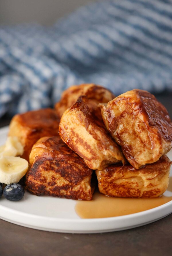 Hawaiian roll French toast with syrup and fruit on the side.