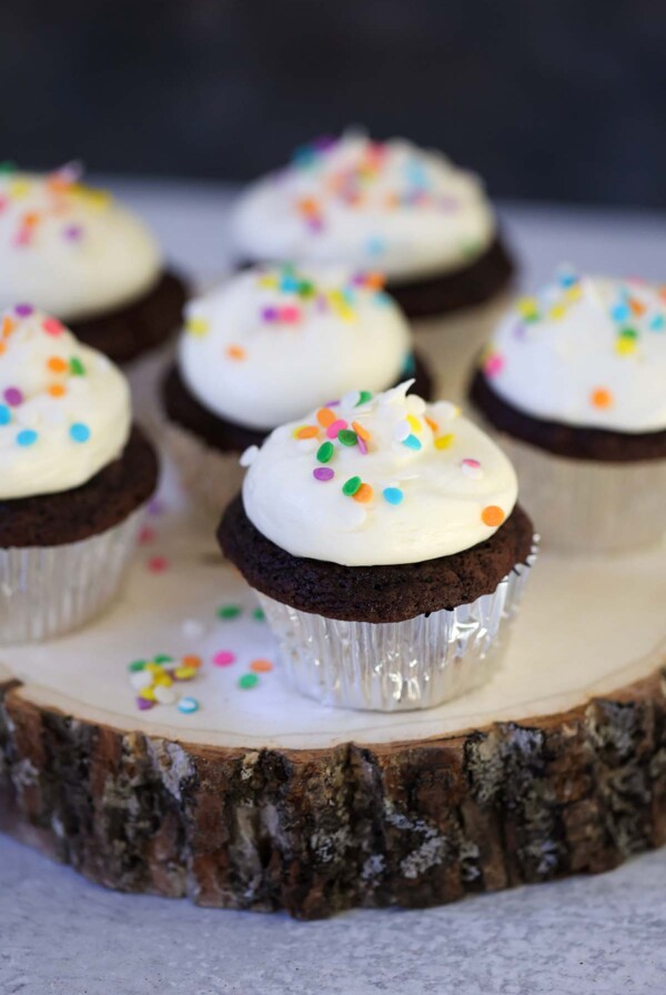 Six chocolate cupcakes with cream cheese frosting and sprinkles.