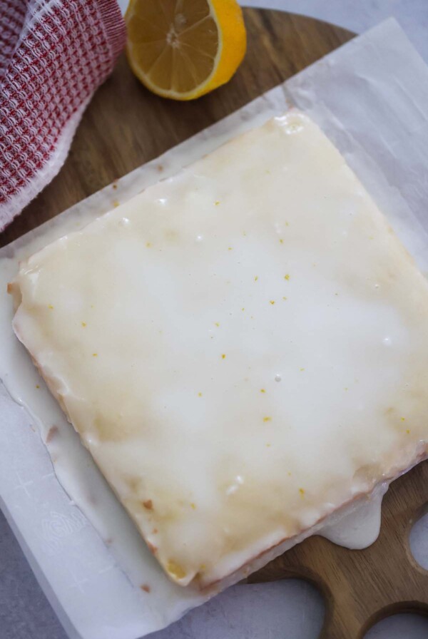 white chocolate lemon blondies on a cutting board with a lemon on the side.