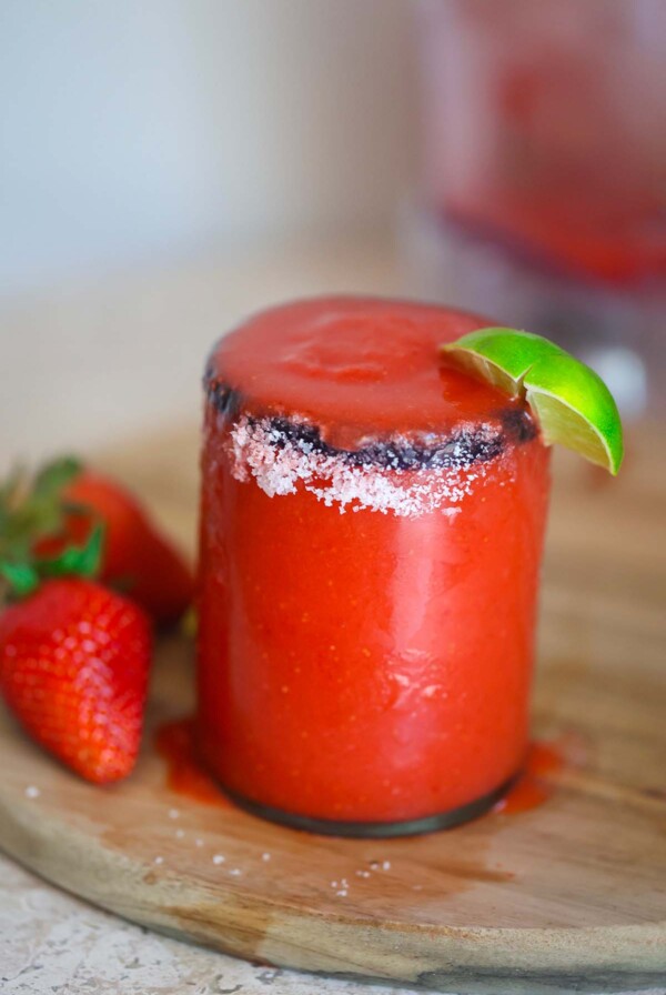 frozen strawberry margarita in a glass with salt on the rim.