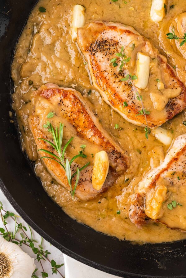 pan seared pork chops with gravy in a cast iron skillet.