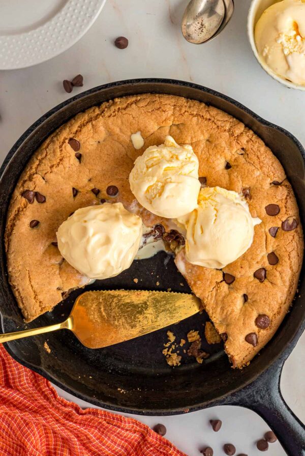 Chocolate chip cookie skillet with three scoops of vanilla ice cream.