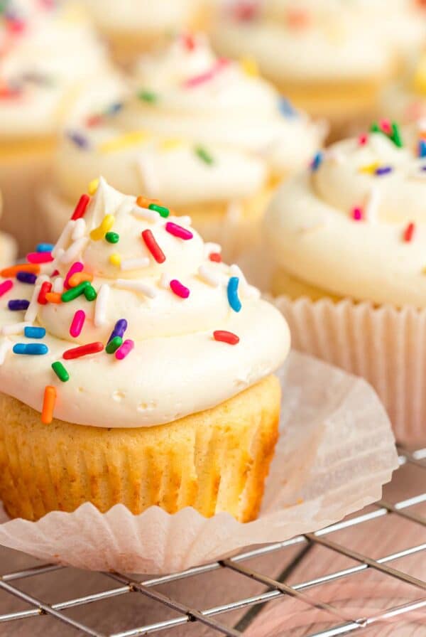 Vanilla cupcake with white frosting and rainbow sprinkles.
