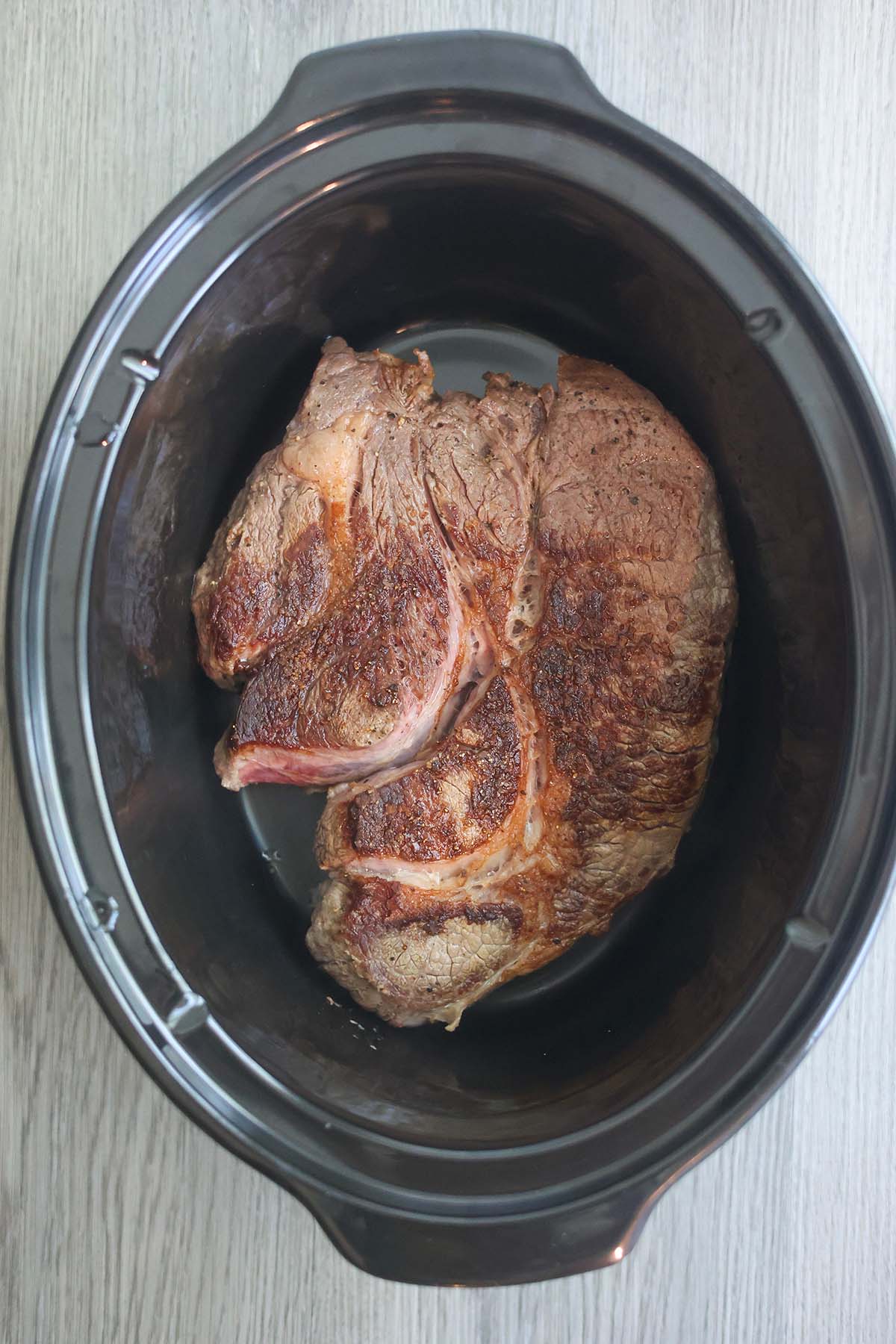 Seared chuck roast beef in a slow cooker. 