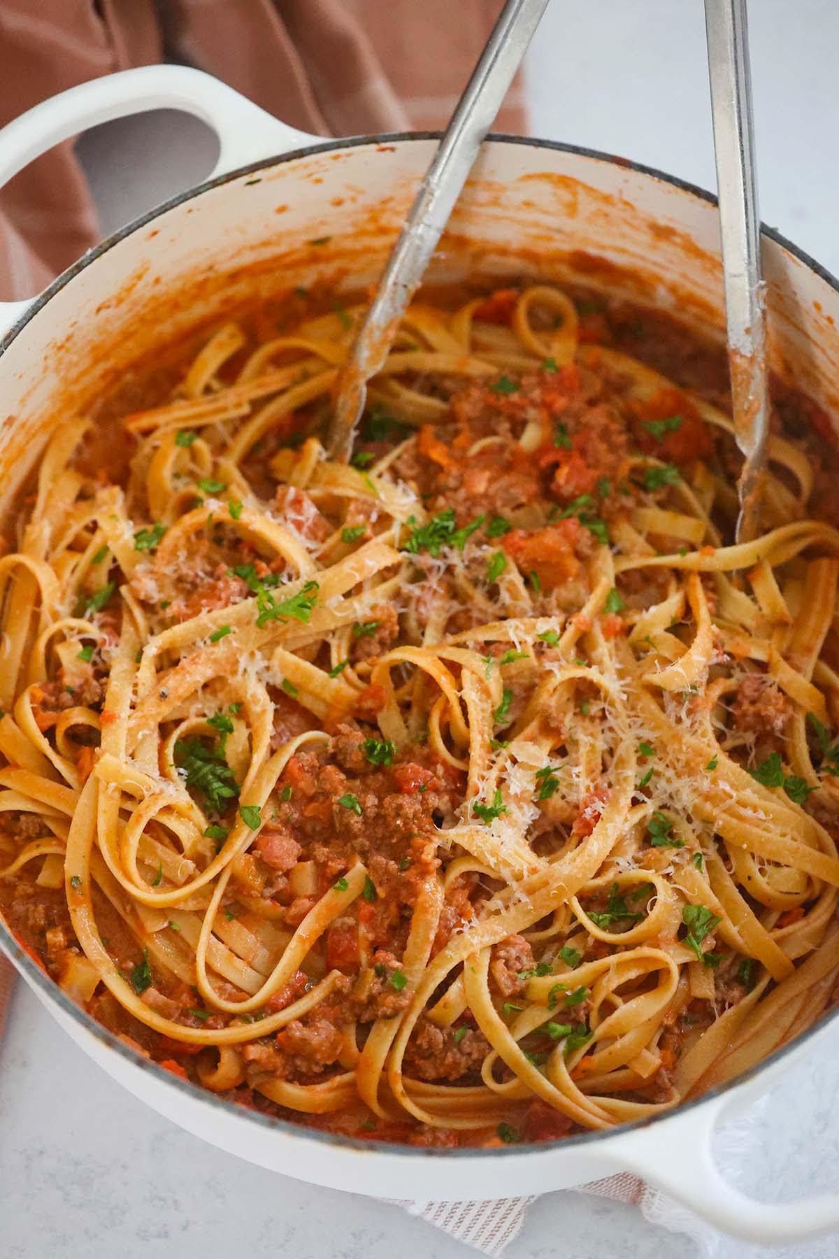 Pasta in a large pot with tongs. 