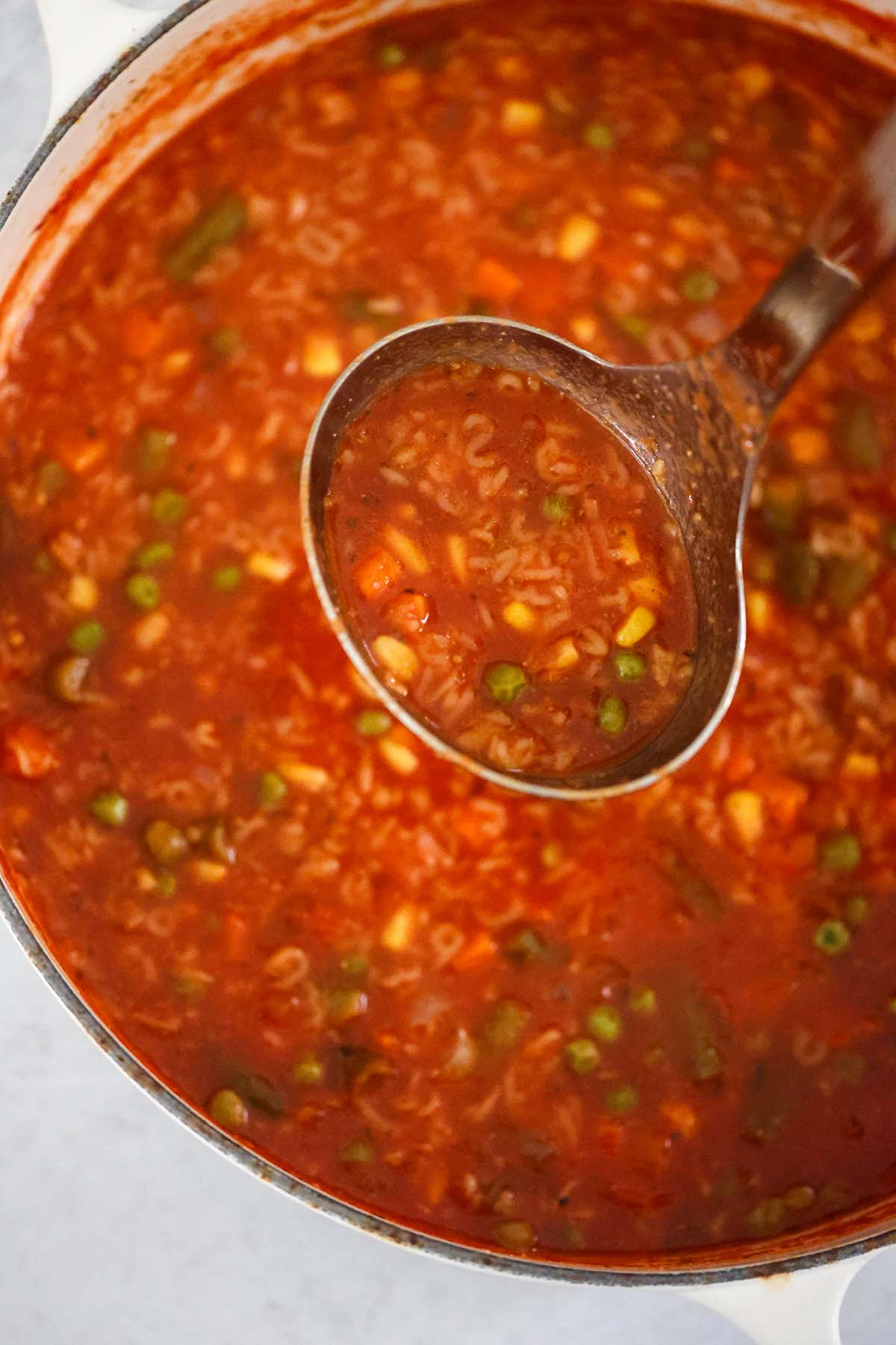 Soup in a large dutch oven with a ladle. 